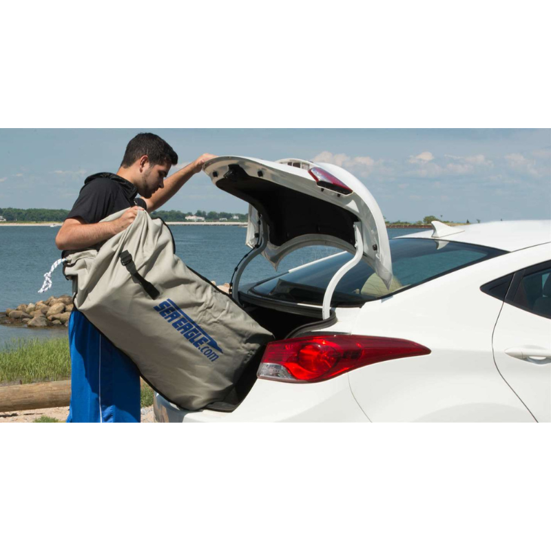 Sea Eagle SE9 Motor Mount Inflatable Boat Person loading a large beige bag into the trunk of a white car by a waterfront.