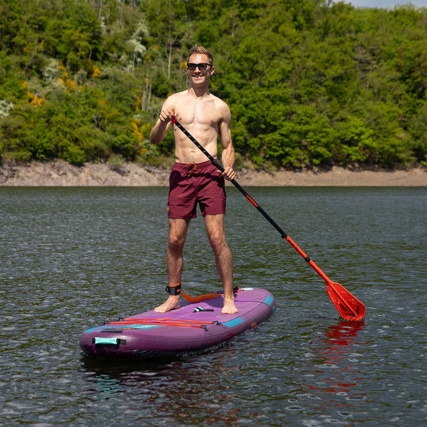 Man paddleboarding on a lake with trees in the background