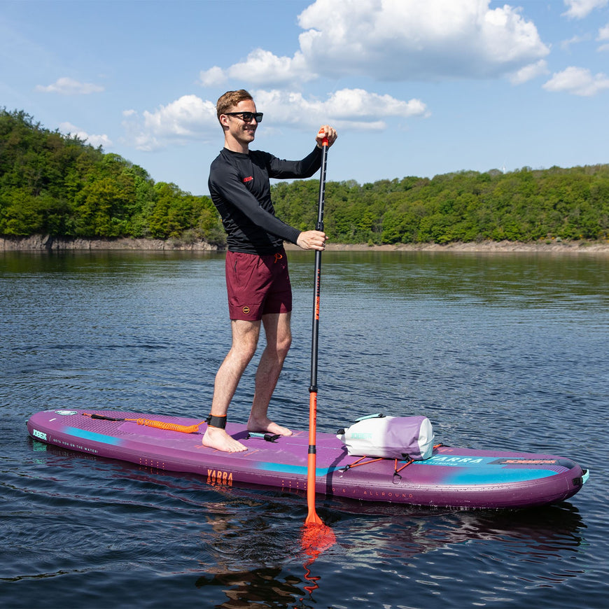 Man paddleboarding on a lake with trees in the background